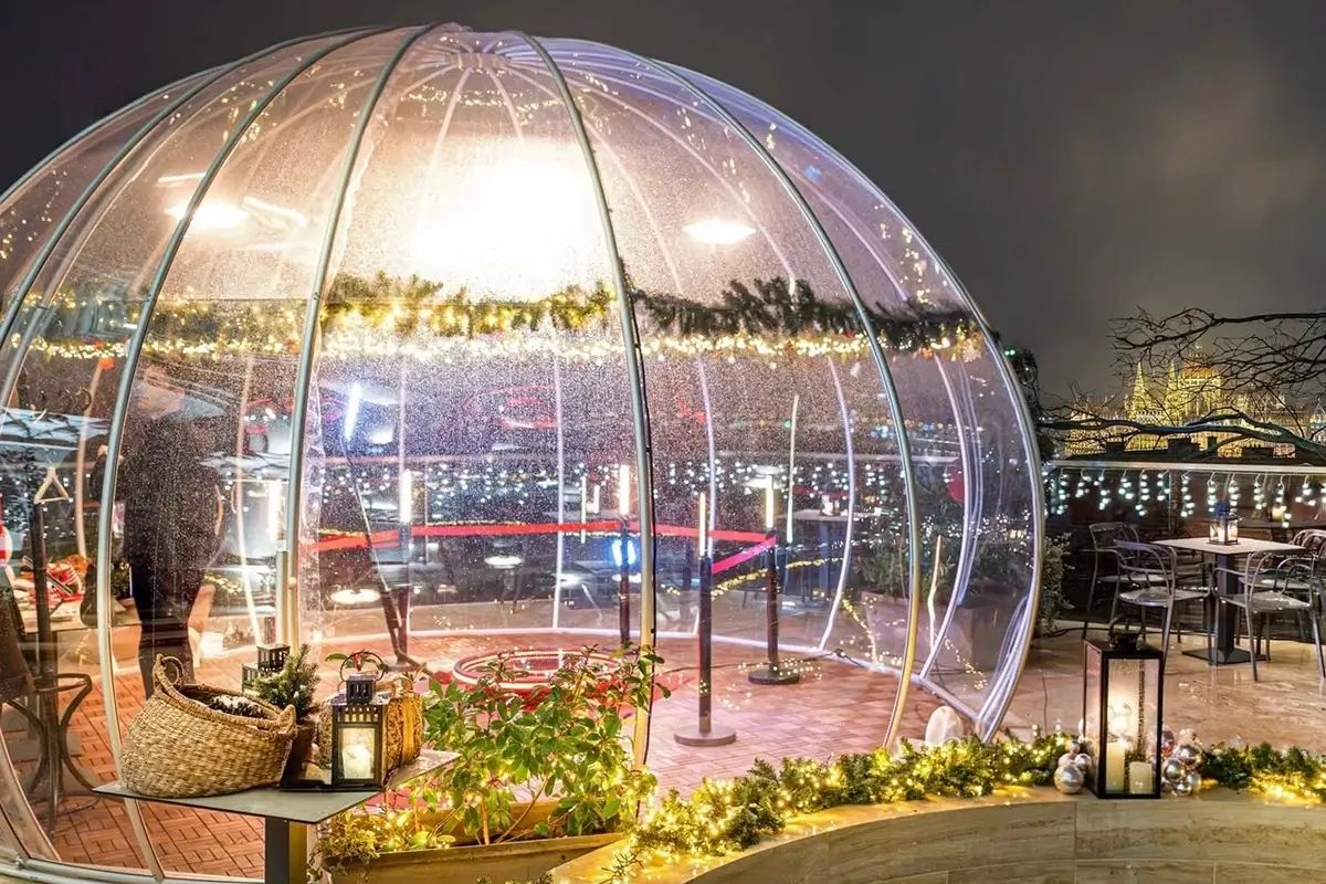 Fenyőfüzérrel díszített, kivilágított igloo egy esti teraszon