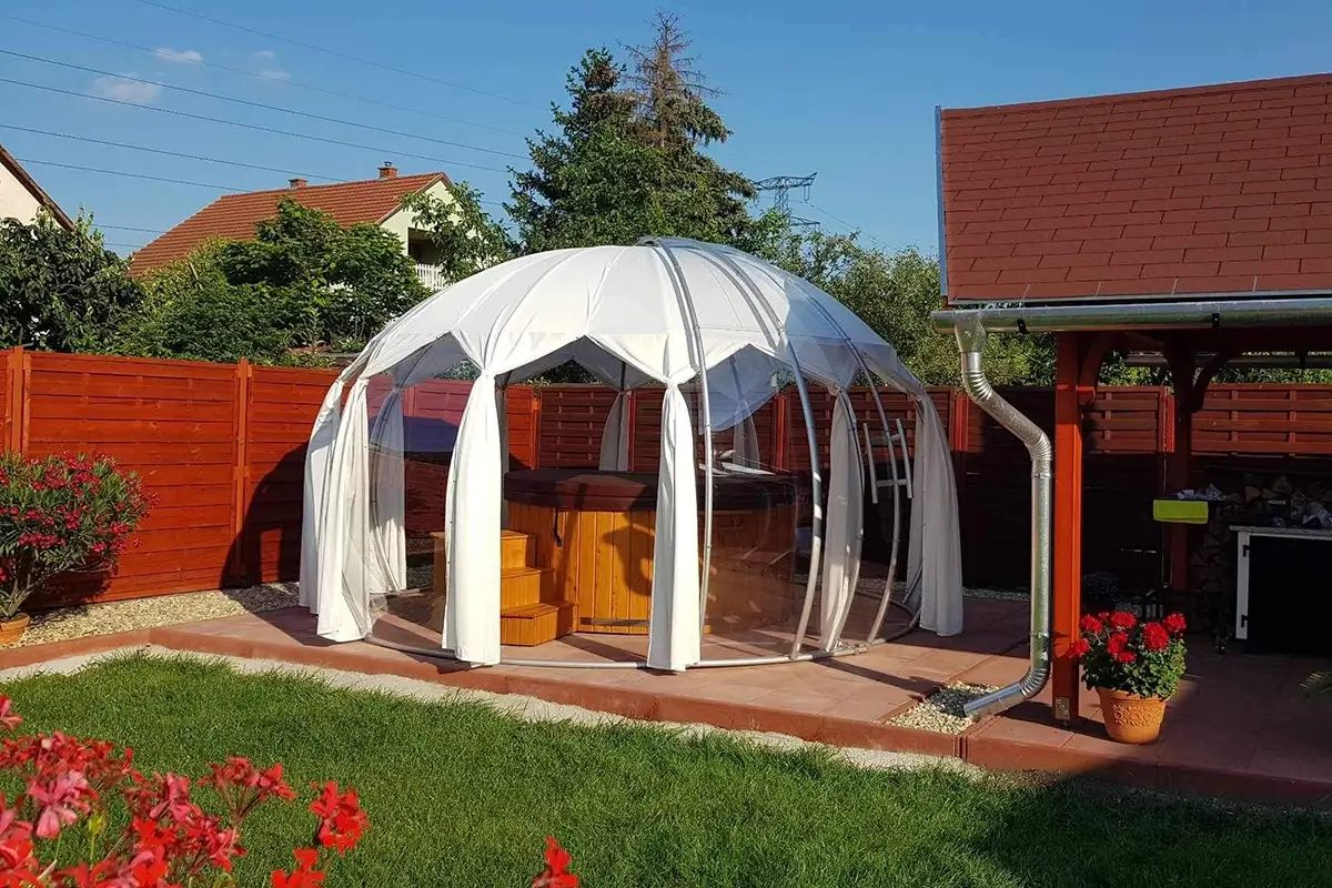 Weißes Igloo mit Sonnenschutz-Bezug über einem Whirlpool im Garten eines Einfamilienhauses