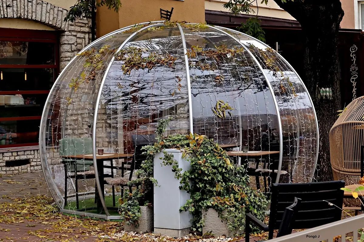 Polikarbonát igloo asztalokkal egy étterem előtt, őszi levelek és borostyán