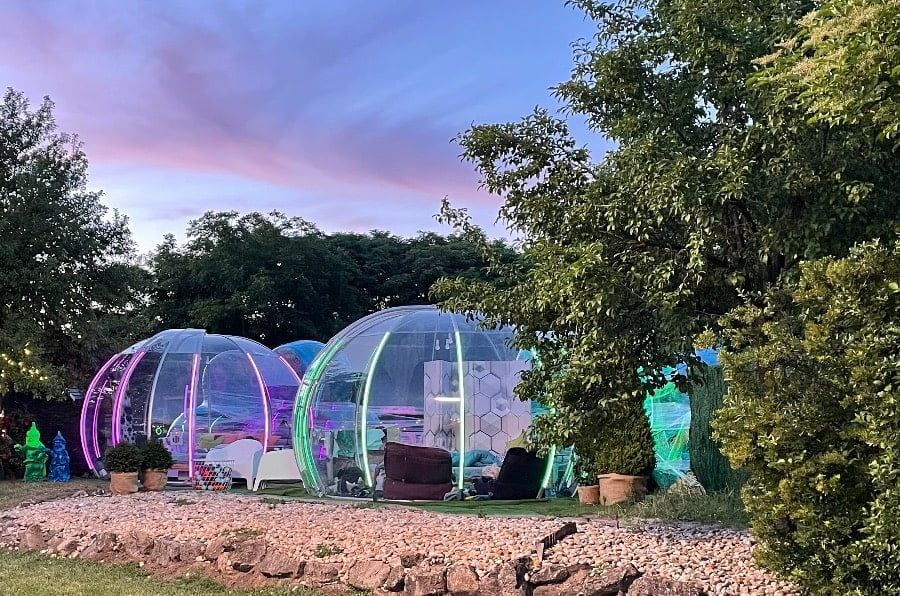 Színes LED-fényekkel megvilágított glamping iglook egy kertben alkonyatkor