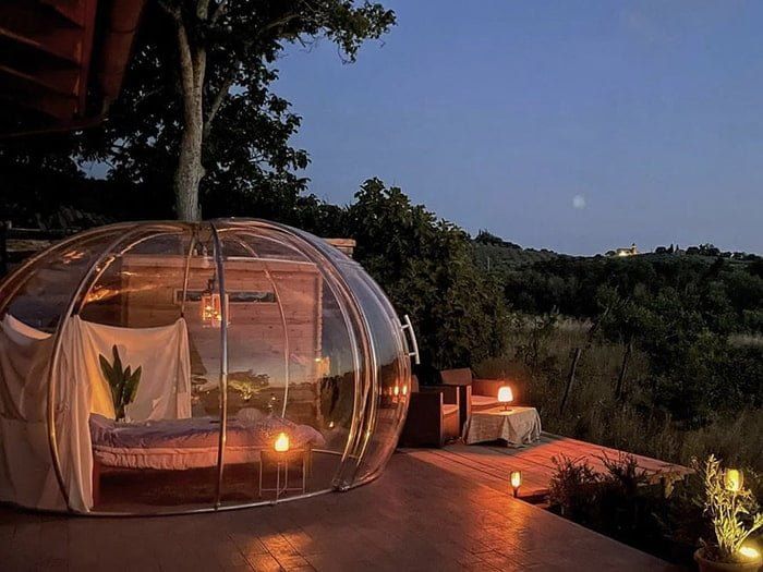 Glamping igloo franciaággyal egy teraszon este, mécsesekkel