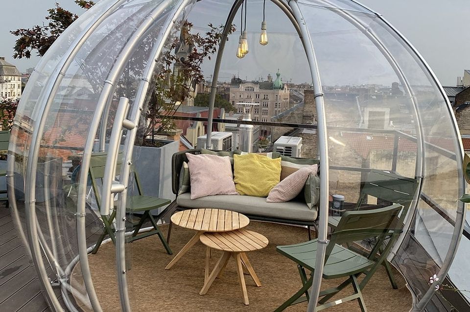 Lounge kanapé párnákkal és fa dohányzóasztal egy igloo belsejében, egy városi tetőteraszon
